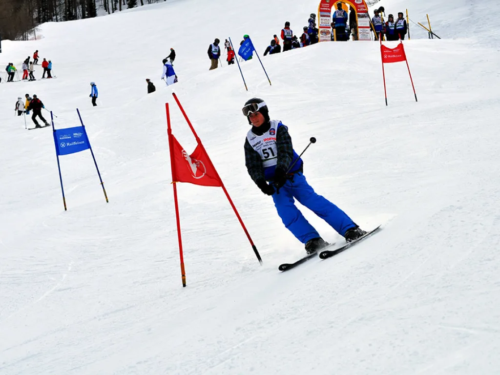Skifahrer in blauer Kleidung zwischen rotem und blauem Tor.